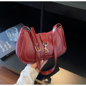 Détail d'un sac sous le bras en cuir verni bordeaux avec boucle en métal doré