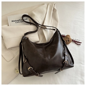 Détail d'un sac hobo vintage marron foncé montrant le cuir PU mat et les boucles en métal