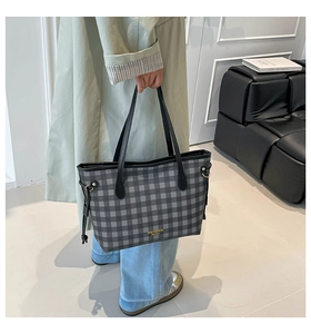 Detail of grey-black plaid tote bag with gold logo print and side drawstring accents