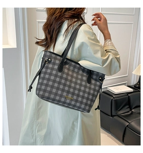 Close-up of black gingham tote bag with gold logo and side drawstring detail