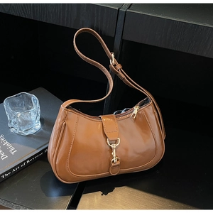 Détail d'un sac baguette croissant marron avec boucle en métal doré sur étagère