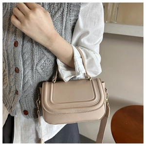 Close-up of beige crossbody bag featuring U-shaped stitching and a wide shoulder strap