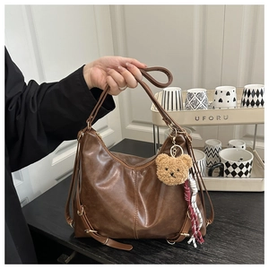 Détail du sac cabas en cuir souple marron foncé avec ferrures dorées et breloque ours
