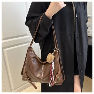 Détail d'un cabas vintage en cuir marron brillant avec pendentif ours en peluche