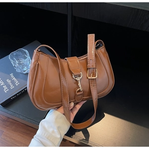 Détail du sac baguette marron brillant avec boucle en métal doré et coutures lisses