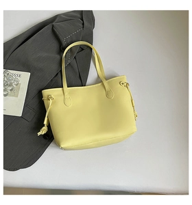 Detail of light yellow tote bag featuring side decorative knots and smooth faux leather