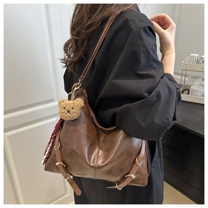 Détail du sac fourre-tout marron vintage avec breloque ours et ruban à carreaux