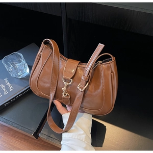 Détail d'un sac baguette en cuir marron avec boucle à piston argentée et bandoulière réglable