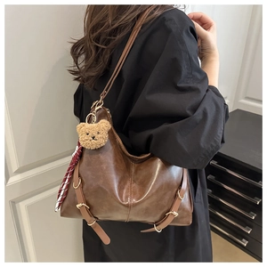 Détail du sac fourre-tout marron vintage avec porte-clés ours en peluche et foulard en soie