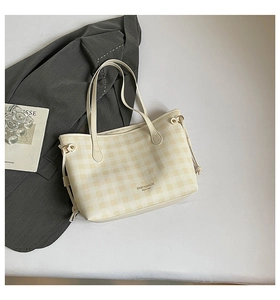 Detail of beige checkered tote bag with double handles and side drawstring accent
