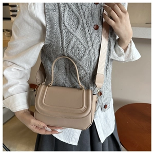 Chic beige small square leather bag with top handle and wide strap on model
