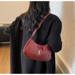 Détail du sac hobo bordeaux avec boucle argentée porté sur un blazer noir chic