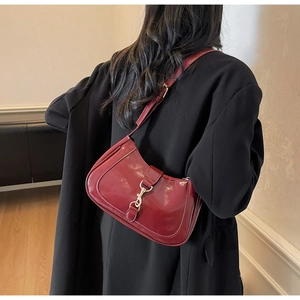 Détail du sac à bandoulière en cuir verni bordeaux avec fermoir piston en argent