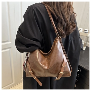 Détail d'un sac hobo marron vintage avec foulard en soie et boucle en métal sur modèle