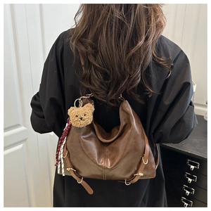 Détail du sac cabas en cuir marron foncé avec breloque ours et écharpe à carreaux