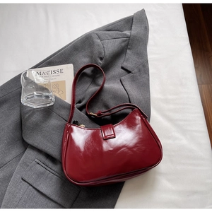 Gros plan détaillé d'un sac à bandoulière en cuir verni rouge foncé dans un décor chic