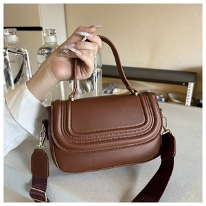 Detail of brown faux leather handbag showing U-shaped stitching and wide purple strap