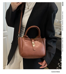 Petit sac à main marron avec boucle en métal doré et bandoulière sur une veste noire