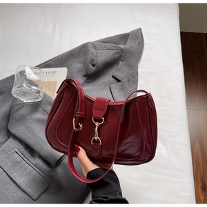 Détail du sac baguette en cuir verni bordeaux avec un fermoir en métal doré chic