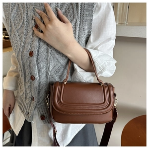 Detailed close-up of brown leather crossbody bag with ribbed stitching and gold hardware