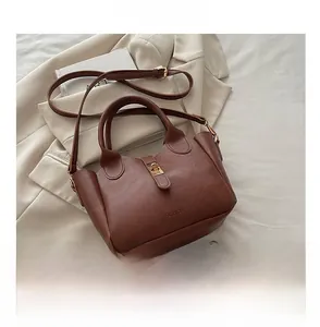 Détail du sac seau en cuir marron avec fermoir doré et téléphone pour l'échelle de taille