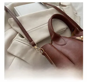 Détail d'un sac à main en cuir grainé marron foncé avec accessoires en métal doré