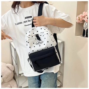 Détail du sac à dos blanc à étoiles avec poche noire porté par un mannequin