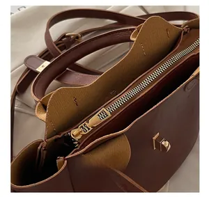 Détail de sac seau marron foncé avec fermeture éclair dorée et boucle métallique