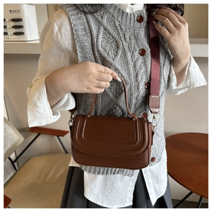 Detail of vintage brown leather crossbody bag featuring stitched flap and wide canvas strap