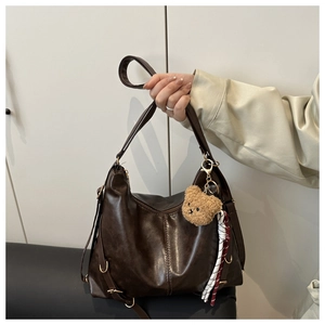 Détail d'un grand cabas en similicuir marron avec breloque ours en peluche et ruban rayé