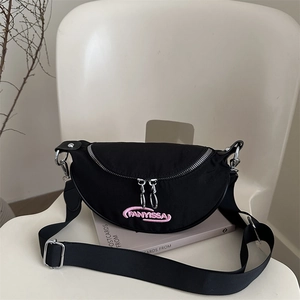 Black crescent chest bag with pink embroidery on white chair, adjustable strap design