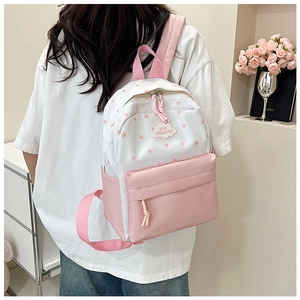 Détail du sac à dos rose et blanc avec motifs d'étoiles et écusson en forme de nuage