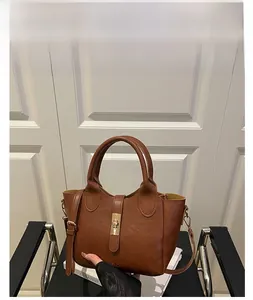 Détail d'un sac seau en cuir marron avec fermoir tournant doré et bandoulière réglable