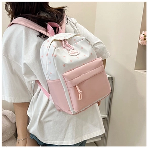 Détail d'un sac à dos rose et blanc à motifs d'étoiles avec un pendentif nuage
