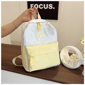 Détail du motif d'étoiles jaunes et du logo nuage sur le sac à dos couleur crème