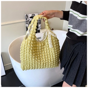 Detail of yellow puffy cloud bag with pleated texture and white lace bow decoration