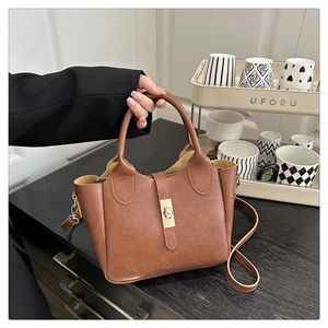 Détail d'un sac seau en cuir marron avec fermoir doré et logo de mode en relief