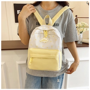 Détail d'un sac à dos jaune avec motifs d'étoiles et logo nuage sur un modèle