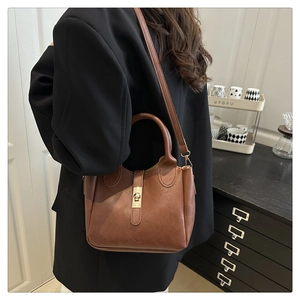 Détail d'un sac seau vintage en cuir marron avec fermoir rotatif et coutures précises