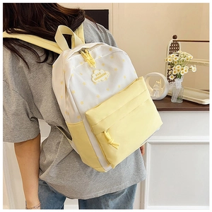 Détail du sac à dos en toile blanc et jaune avec motif étoile et logo en forme de nuage