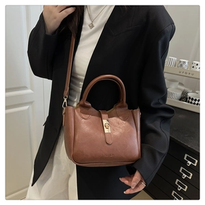 Détail du sac seau en cuir marron avec boucle métallique et bandoulière réglable