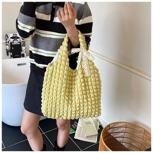 Close-up of yellow popcorn textured tote bag with delicate lace bow detail