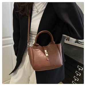 Détail du sac seau vintage en cuir marron avec fermoir doré et logo embossé