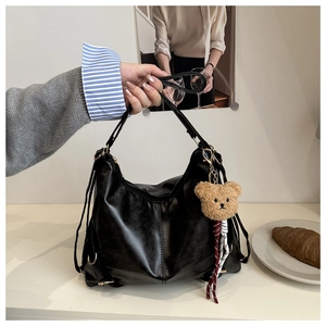 Détail d'un grand sac à main noir en similicuir avec un charmant petit ours en peluche