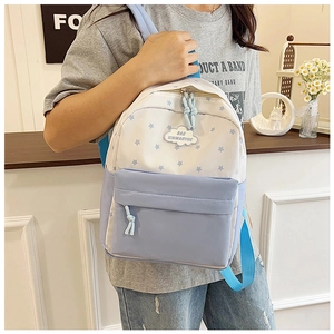 Vue latérale d'un mini sac à dos bleu clair et blanc avec motif étoilé porté par une femme