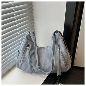 Detail of light grey blue tote bag with unique pleated texture and silver tassel zippers