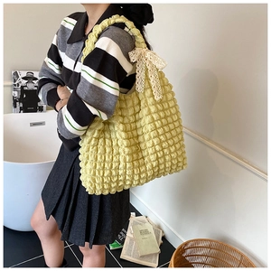 Close-up of pale yellow popcorn texture tote bag featuring a delicate lace bow detail