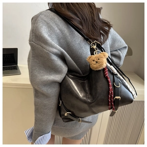 Détail du sac cabas en cuir noir avec breloque ours en peluche et boucle métallique