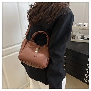 Détail d'un sac seau marron texturé avec fermoir doré et logo de mode sur le devant