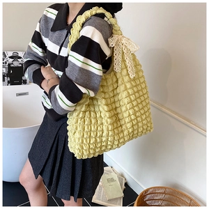 Detail of light yellow popcorn texture shoulder bag with cream lace bow accent